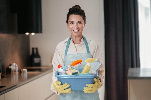 Housewife. Young smiling woman with a basin with cleansing appliances