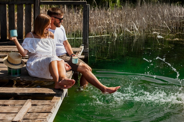 Hugging couple playing with their feet in the water