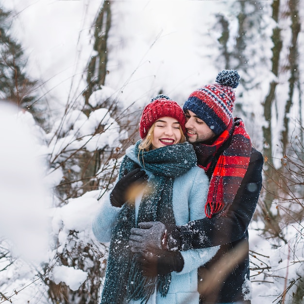 Hugging happy couple in winter woods