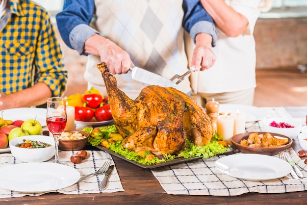 Free photo human cutting roasted chicken on tray near people