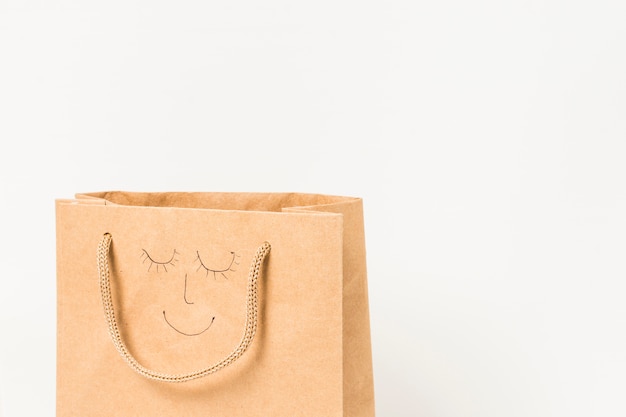 Free Photo human face drawn on brown paper bag against white surface