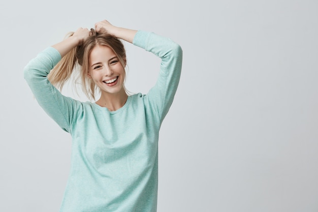 Human face expressions and emotions. Positive young beautiful female with dyed blonde straight hair in ponytail dressed in casual clothing