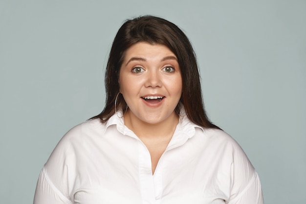 Human facial exppressions and reaction. Attractive emotional young businesswoman with curvy body posing with mouth wide opened, stunned with positive news, expressing great excitement