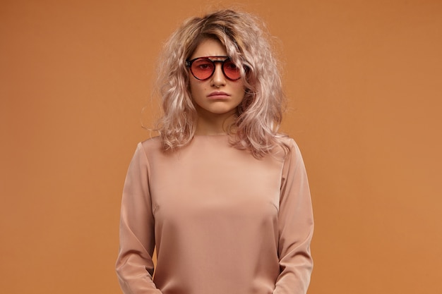 Free photo human facial expressions and emotions. dissatisfied upset young female wearing stylish sunglasses being in bad mood, having bored look