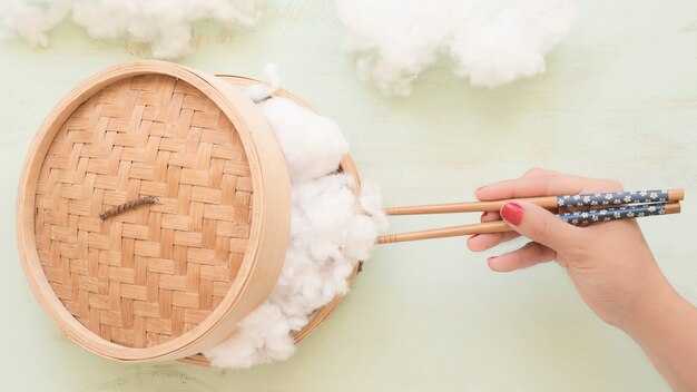 Human hand holding cotton with chopsticks from steamer