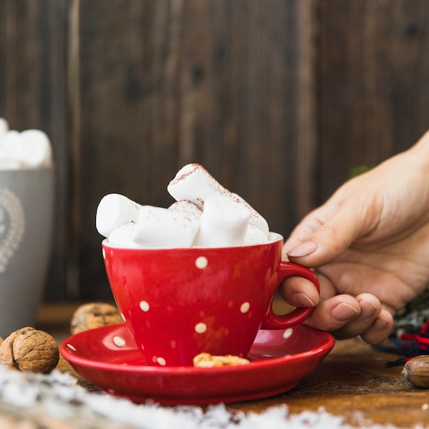 Human hand holding cup with marshmallow