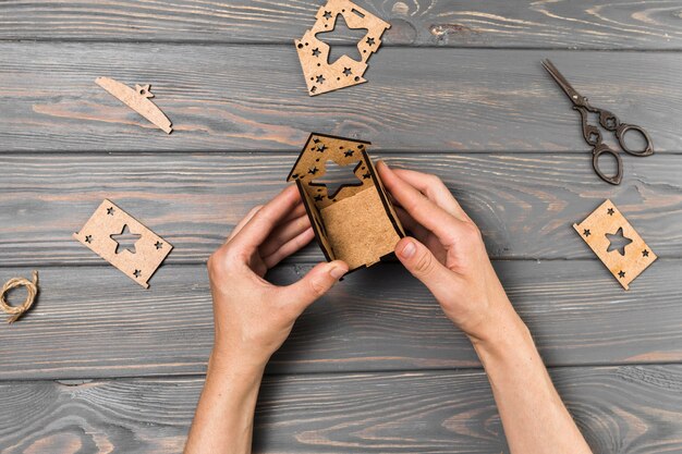 Human hand making house from cardboard on wooden desk