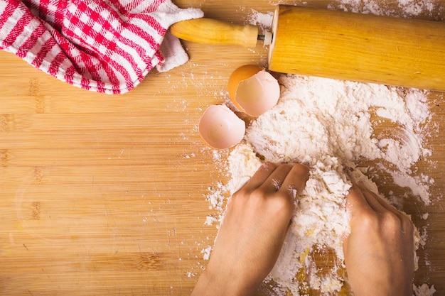 Human hand mixing flour with egg on wooden desk