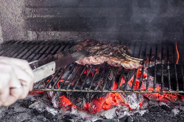 Free photo human hand roasting meat in barbecue grill