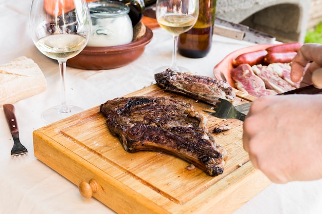 Free Photo human hand slicing meat on wooden chopping board