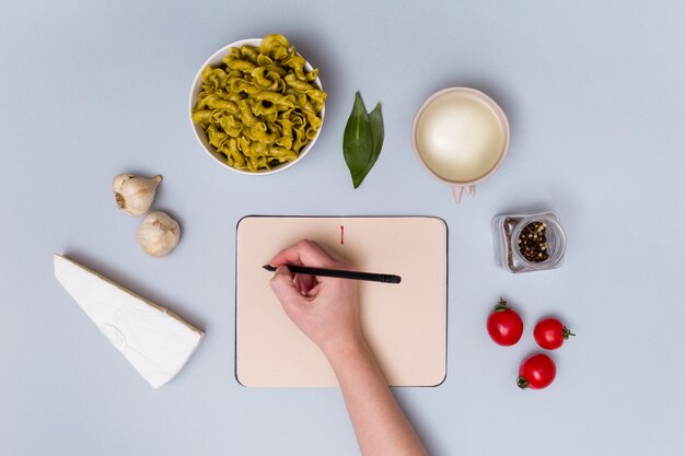 Free Photo human hand writing on diary surrounding by pasta ingredient