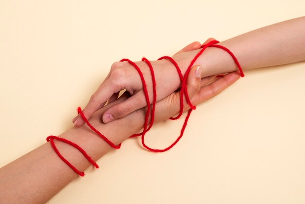 Human hands connected with red thread