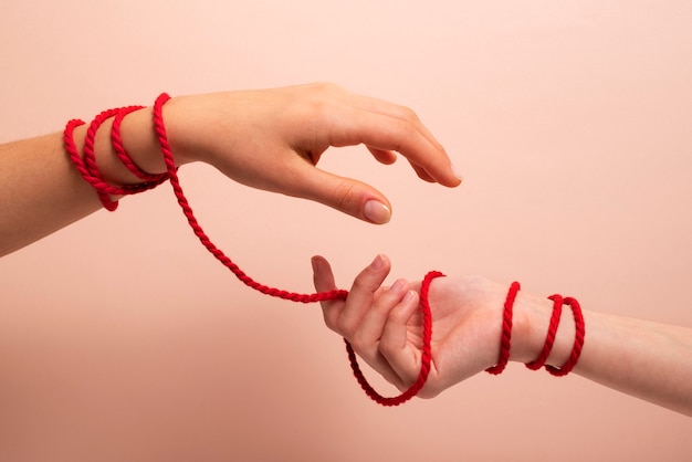 Human hands connected with red thread