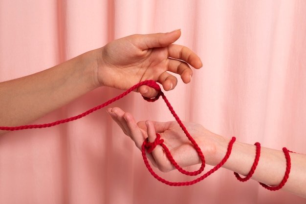 Human hands connected with red thread