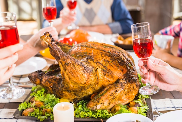 Human hands holding glasses at table with food