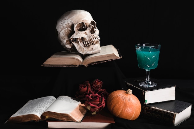 Free photo human skull with green drink and books