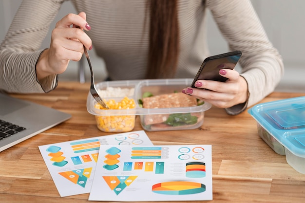 Free photo hungry businesswoman eating and working on phone