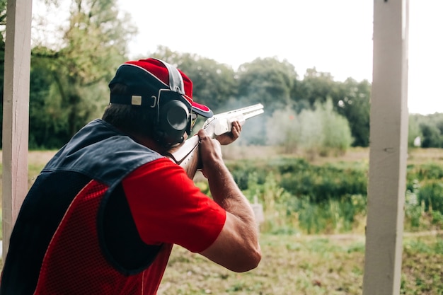 Free Photo hunter shoots with a shotgun on a target in special clothes and headphones