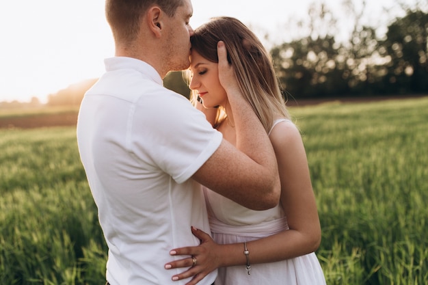 Free photo the husband kissing his wife and standing on the field