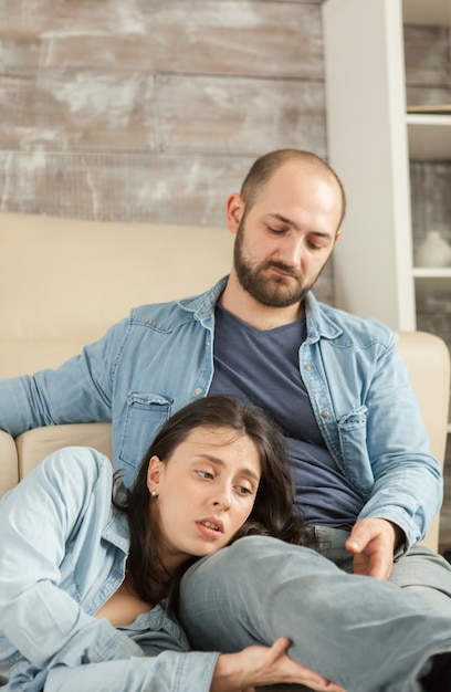 Husband looking at wife while resting together on living room rug