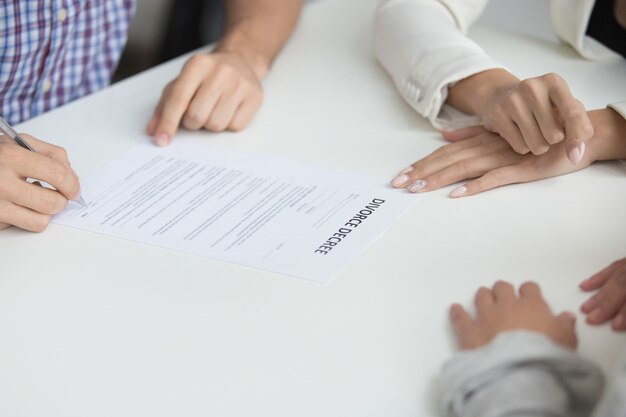 Husband signing divorce decree giving permission to marriage dissolution, closeup