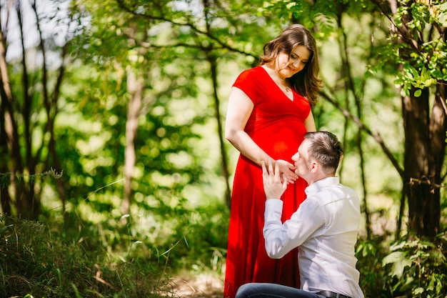 The husband  with pregnant wife embracing in the forest