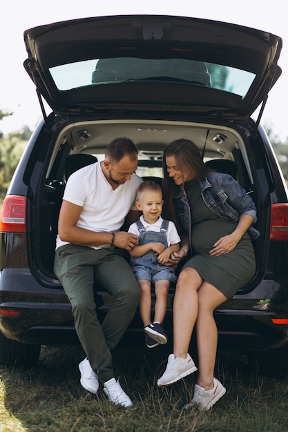 Husband with pregnant wife and their son sitting in car