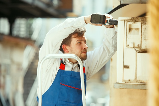 Free photo hvac technician working on a capacitor part for condensing unit