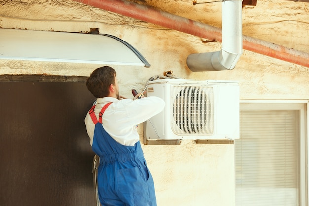 Free photo hvac technician working on a capacitor part for condensing unit