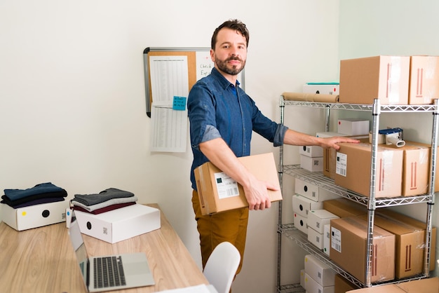 Free photo i have a growing business. portrait of a handsome entrepreneur smiling and making eye contact while preparing packages ready to ship to customers