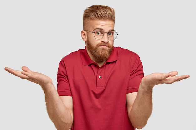 Free Photo i know nothing. handsome stylish hipster with thick ginger beard, spreads palms with questionned expression