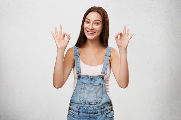 I'm doing great. Joy and happiness. Picture of glad happy young female smiling broadly and making ok gesture with both hands, rejoicing at good day, life goals or achievements. Body language