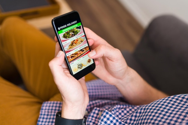 I'm hungry. Hands of a man looking at a food delivery app on his smartphone and ordering dinner online