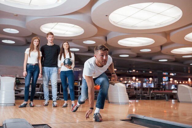 I wanna strike. Young cheerful friends have fun in bowling club at their weekends