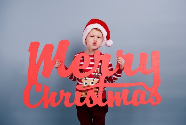 I wish you merry christmas. Boy with merry christmas lettering