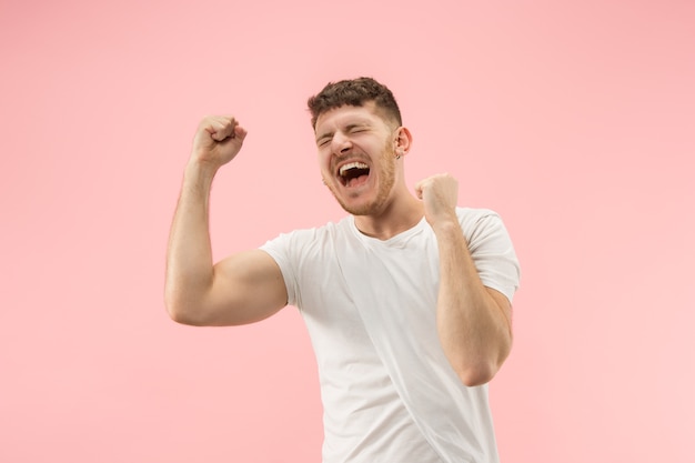 Free photo i won. winning success happy man celebrating being a winner. dynamic image of caucasian male model on pink studio background.