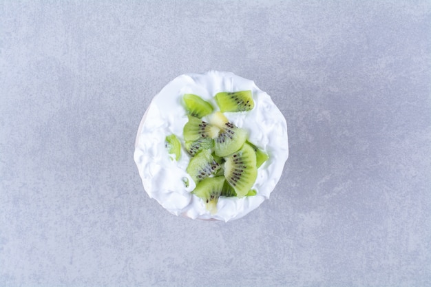 Free photo ice cream in a glass pedestal with slices kiwi on marble table.