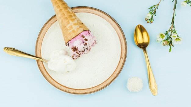 Free photo ice cream near spoons on plate near flowers