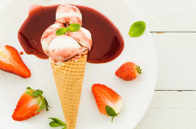 Free Photo ice cream in waffle cone with strawberry syrup