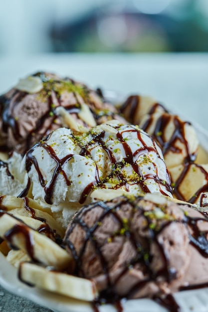 Free photo ice-cream with bananas, chocolate and sprinkles on the white plate