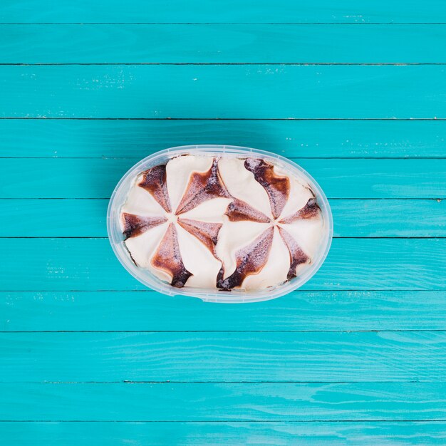 Ice cream with chocolate in plastic bowl on wooden surface