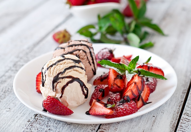 Free Photo ice cream with strawberries and chocolate on a white plate