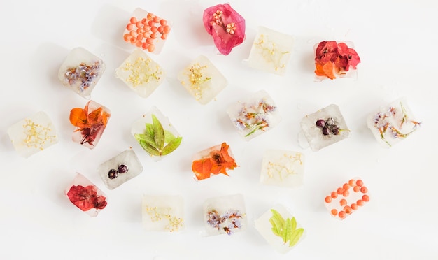 Free photo ice cubes with bright flowers on white background