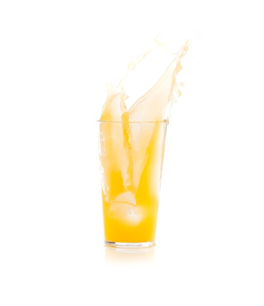 Ice falling into a glass with yellow drink