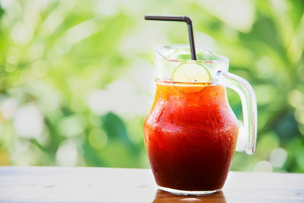 Ice tea on wooden table over green garden - relax with beverage in nature concept