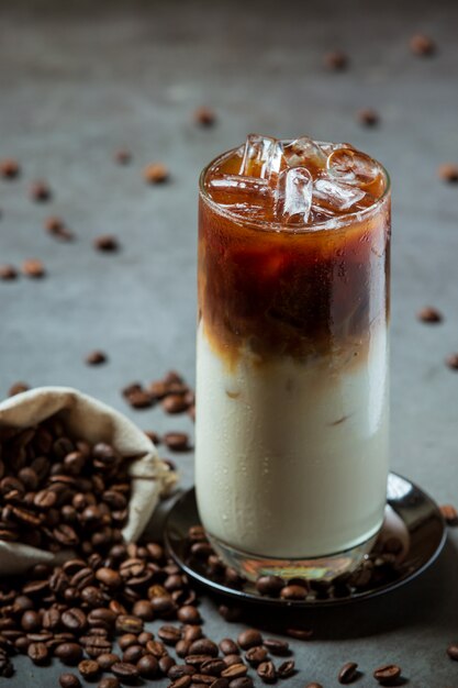 Iced coffee in a tall glass with cream topped with iced coffee decorated with coffee beans.