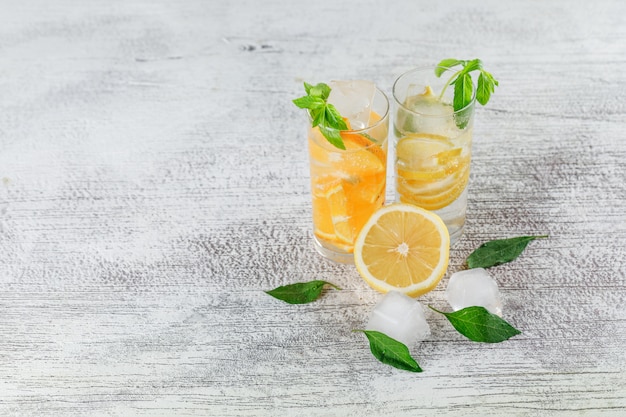 Free photo icy detox water in glass with orange, lemon, mint high angle view on a grunge background