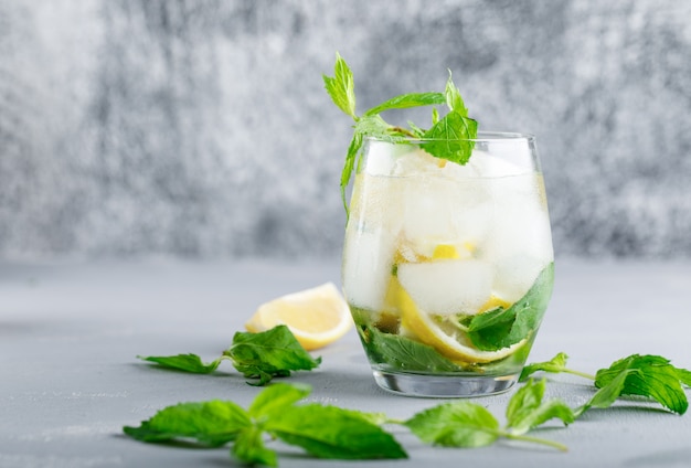 Free photo icy detox water with lemon and mint in a glass on grey and grunge surface