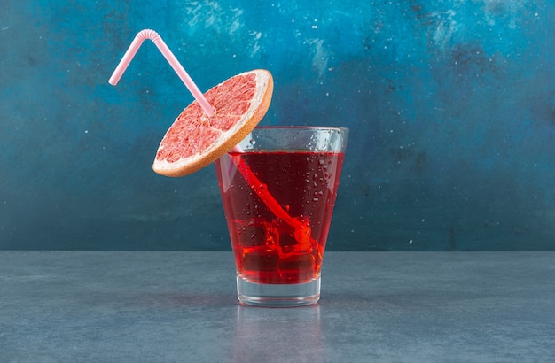 Free Photo icy glass of juice adorned with a straw pipe and a fresh slice of grapefruit on blue background. high quality photo