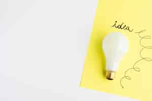 Free photo idea text written on adhesive note with light bulb over white background